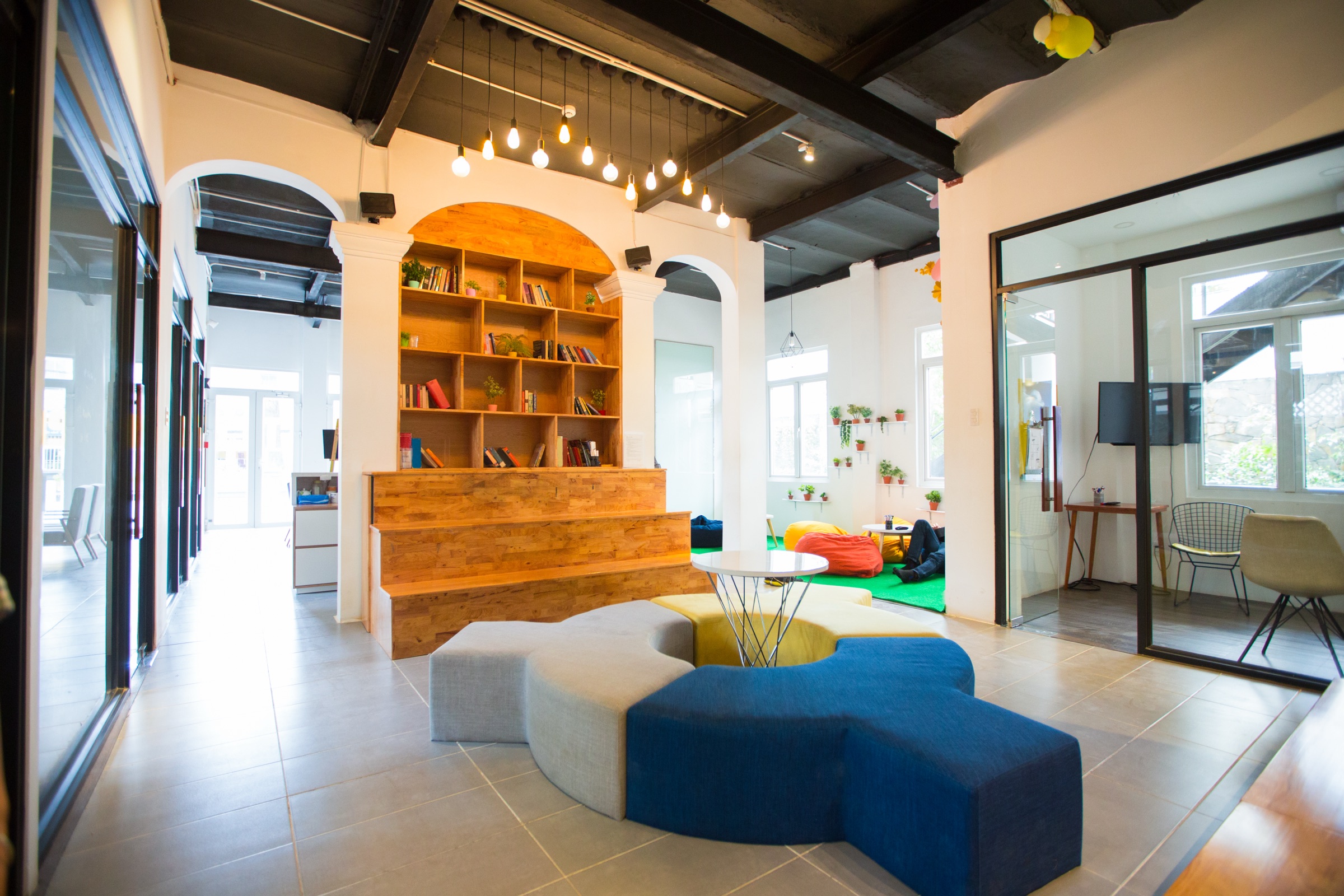 A vibrant breakout lounge with a bespoke timber library wall, modular soft seating and exposed beams